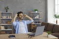 Happy young man sitting at desk with laptop, feeling excited, smiling and fist pumping Royalty Free Stock Photo