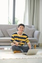 Happy young man sitting on a floor with laptop computer in a living room Royalty Free Stock Photo