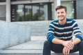 Happy young man sitting in front of entry entrance Royalty Free Stock Photo