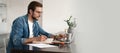 Happy young man sitting in home office and using laptop computer, smiling, chatting online Royalty Free Stock Photo