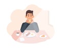 Happy young man sitting at table and eating delicious morning meal. Male character having breakfast at home. Smiling boy Royalty Free Stock Photo