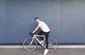 Happy young man sitting on a white bike against the wall, looking at the camera and smiling Royalty Free Stock Photo