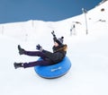 Happy young man sliding down on snow tube