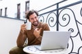Happy young man smiling, as he works on his laptop to get all his business done early in the morning with his cup of coffee Royalty Free Stock Photo