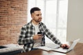 Happy young man, smiling, as he works on his laptop to get all his business done early in the morning with his cup of coffee Royalty Free Stock Photo