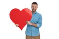 Happy young man smiling, holding big red heart