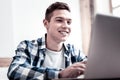 Happy young man smiling and looking at the screen of his laptop Royalty Free Stock Photo