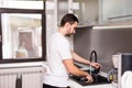 Happy young man standing and washing dishes on the kitchen Royalty Free Stock Photo