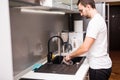 Happy young man standing and washing dishes on the kitchen Royalty Free Stock Photo