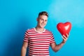 A young man in a studio, holding red heart balloon in his hand. Royalty Free Stock Photo