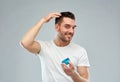 Happy young man styling his hair with wax or gel Royalty Free Stock Photo