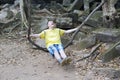 Happy young man, the teenager, the tourist, shakes on a liana as on a swing on Beng Mealea temple ruin in the Koh Ker complex, Si Royalty Free Stock Photo