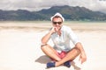 Happy young man thinking while sitting on beach Royalty Free Stock Photo