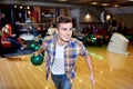 Happy young man throwing ball in bowling club Royalty Free Stock Photo