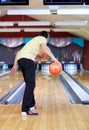 Happy young man throwing ball in bowling club