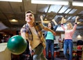 Happy young man throwing ball in bowling club Royalty Free Stock Photo