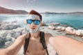 Happy young man tourist takes a selfie photo at a therapeutic mud resort at Dead sea. He applied natural cosmetic clay to face