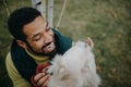 Happy young man training and cuddling with his dog outdoors in city park, during cold autumn day. Royalty Free Stock Photo