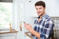 Happy young man using cell phone on the kitchen Royalty Free Stock Photo