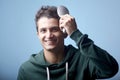 Happy young man using hairbrush in front of light blue back Royalty Free Stock Photo