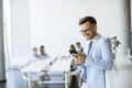 Happy young man using his mobile phone and smiling while his colleagues working in the background Royalty Free Stock Photo