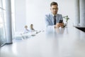 Happy young man using his mobile phone and smiling while his colleagues working in the background Royalty Free Stock Photo