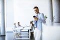 Happy young man using his mobile phone and smiling while his colleagues working in the background Royalty Free Stock Photo