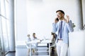 Happy young man using his mobile phone and smiling while his colleagues working in the background Royalty Free Stock Photo