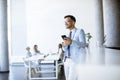 Happy young man using his mobile phone and smiling while his colleagues working in the background Royalty Free Stock Photo