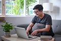 Young man using laptop computer in living room at home. Royalty Free Stock Photo