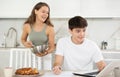 Happy young man using laptop in the kitchen while communicating with his girlfriend Royalty Free Stock Photo