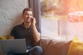 Happy young man using laptop and mobile phone on couch Royalty Free Stock Photo