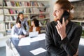 Happy young man using mobile phone and smiling while his colleagues working in office Royalty Free Stock Photo