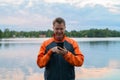 Happy Young Man Using Phone By The Lake Royalty Free Stock Photo