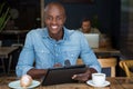 Happy young man using tablet computer at table in coffee shop Royalty Free Stock Photo