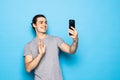 Happy young man video calling, talking online with mobile phone, saying hello to smartphone camera and waving hand friendly, Royalty Free Stock Photo