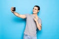 Happy young man video calling, talking online with mobile phone, saying hello to smartphone camera and waving hand friendly, Royalty Free Stock Photo