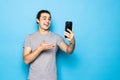 Happy young man video calling, talking online with mobile phone, saying hello to smartphone camera and waving hand friendly, Royalty Free Stock Photo