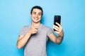 Happy young man video calling, talking online with mobile phone, saying hello to smartphone camera and waving hand friendly, Royalty Free Stock Photo