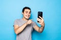 Happy young man video calling, talking online with mobile phone, saying hello to smartphone camera and waving hand friendly, Royalty Free Stock Photo