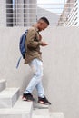 Happy young man walking down stairs with bag and mobile phone Royalty Free Stock Photo