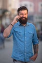 Happy young man walking on the street while talking by mobile phone. Royalty Free Stock Photo