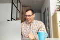 Happy young man wearing glasses gets a good news and smiling as he works on his laptop Royalty Free Stock Photo