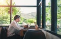 Happy young man, wearing glasses and smiling, as he works on his laptop to get all his business done early in the morning with his Royalty Free Stock Photo