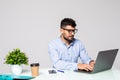 Happy young man, wearing glasses and smiling works on his laptop to get all his business done early in the morning with his cup of Royalty Free Stock Photo