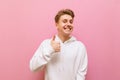 Happy young man in white casual clothes showing thumbs up, smiling and looking into the camera with a smile on his face, isolated Royalty Free Stock Photo