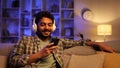 Happy young man with white headphones chilling and listening his favorite song. Arabian brunette man seat on sofa and Royalty Free Stock Photo