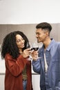 Happy young man and woman drinking with glasses in home. Cheering diverse couple toasting with wine in kitchen. Royalty Free Stock Photo