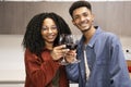 Happy young man and woman drinking with glasses in home. Cheering diverse couple toasting with wine in kitchen. Royalty Free Stock Photo