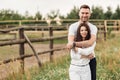 Happy young man and woman having fun outdoors on a warm summer day. couple is hugging in the park near wooden fence Royalty Free Stock Photo